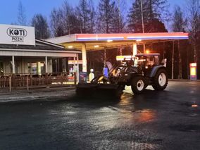 Traktori siistimässä asfalttia huoltoaseman edustalla